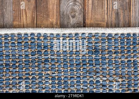 Tappeto in denim geometrico intrecciato a mano su pavimento in legno. Foto Stock