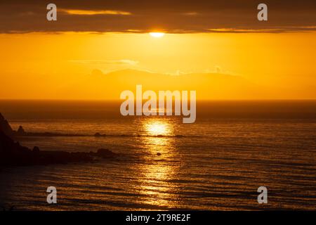 Tramonto sullo stretto di Cook e sull'Isola del Sud, preso da Titahi Bay, Wellington, Isola del Nord, nuova Zelanda Foto Stock