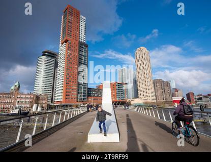 rotterdam, paesi bassi, 25 novembre 2023: la gente cammina e cavalca in bicicletta kop van zuid a rotterdam visto dal rijnhavenbrug nel giorno di sole di novembre Foto Stock