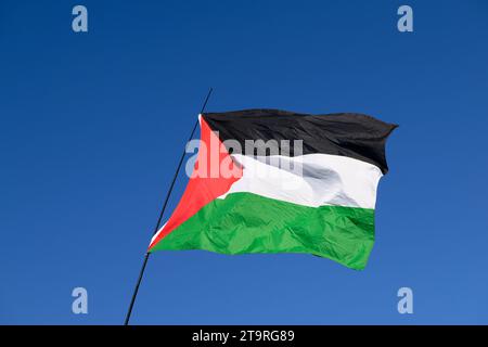 Una bandiera palestinese contro il cielo blu all'inizio di una marcia pro-Palestina ha chiesto il cessate il fuoco dell'offensiva militare in corso a Gaza da parte di Isra Foto Stock