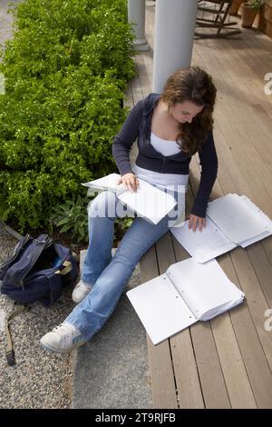 Una ragazza che fa i compiti sui gradini del suo portico. Foto Stock