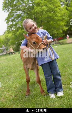 Una bambina che abbraccia una mucca in una fattoria a Madison, CT. Foto Stock