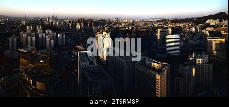 Vista aerea dello skyline della città al tramonto, con sfumature arancioni e rosa che illuminano gli edifici Foto Stock