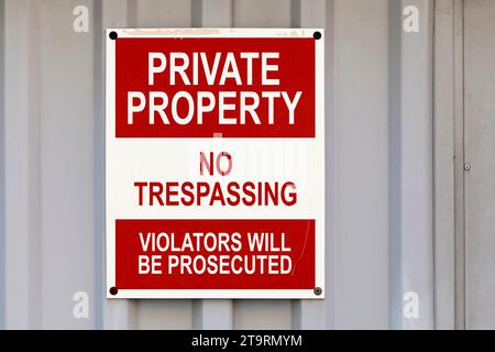 Cartello di avvertimento stampigliato su un cartello rosso e bianco con scritto in "Proprietà privata, nessuna violazione, i trasgressori saranno perseguiti". Foto Stock