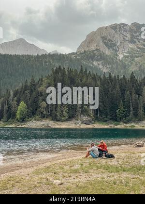 Ragazzo, ragazza e cane che riposano sulla riva del Black Lake Foto Stock