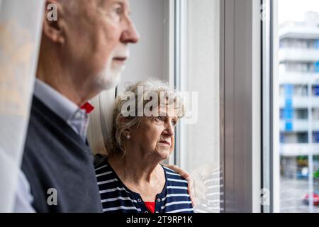 Ritratto di una coppia anziana che guarda fuori dalla finestra di casa Foto Stock