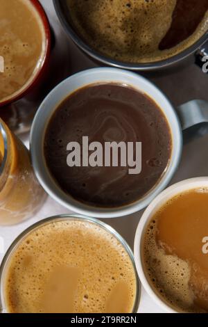 Vista positiva di diversi caffè. Alcuni di loro hanno il latte, altri sono neri, caldi, ghiacciati, su una tovaglia bianca Foto Stock