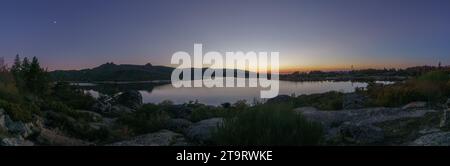 Panorama di crepuscolo serale con luna di mezzaluna sul lago di montagna dopo il tramonto in un paesaggio roccioso puro, vale do Rossim, Serra da Estrela, Portogallo Foto Stock