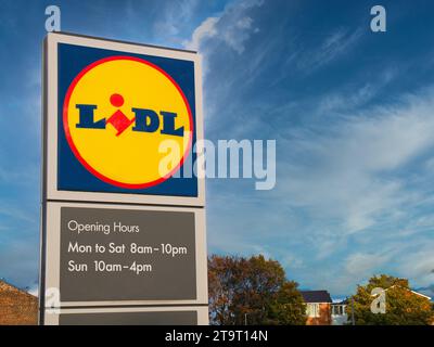 Cartellonistica aziendale all'esterno di un supermercato Lidl nel Regno Unito. Il cartello include il logo dell'azienda giallo, rosso e blu e i dettagli degli orari di apertura. Foto Stock