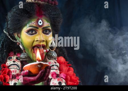 Ritratto della bellissima ragazza indiana di Durga Idol Agomoni Concept foto al coperto che indossa il tradizionale sari indiano, gioielli in oro e braccialetti. Maa Durga. Foto Stock