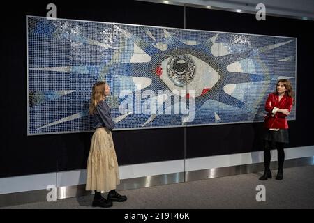 Londra, Regno Unito. 27 novembre 2023. Membri dello staff con "The Psychedelic Eye" Mosaic, circa 1965, creato da Joseph [Joe] ritrovato, un maestro di mattonelle, commissionato da John Lennon per la sua piscina presso la sua casa di Kenwood comprendente circa 17.000 piastrelle policrome e l'Iris formato da piastrelle in vetro specchio (prezzo stimato su richiesta) in anteprima della vendita di Bonhams’ Rock, Pop & Film. La vendita ha luogo nelle gallerie Bonhams Knightsbridge il 29 novembre. Crediti: Stephen Chung / Alamy Live News Foto Stock