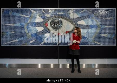 Londra, Regno Unito. 27 novembre 2023. Un membro dello staff con "The Psychedelic Eye" Mosaic, risalente al 1965 circa, creato da Joseph ritrovato, un maestro di mattonelle, commissionato da John Lennon per la sua piscina presso la sua casa di Kenwood comprendente circa 17.000 piastrelle policrome e l'Iris formato da piastrelle in vetro specchio (prezzo stimato su richiesta) in anteprima della vendita di Bonhams’ Rock, Pop & Film. La vendita ha luogo nelle gallerie Bonhams Knightsbridge il 29 novembre. Crediti: Stephen Chung / Alamy Live News Foto Stock