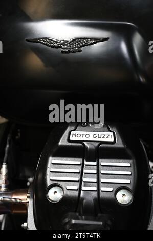 Primo piano del logo e del motore del marchio Moto Guzzi con superficie in metallo lucido trasparente. Famoso marchio italiano di motociclette Foto Stock