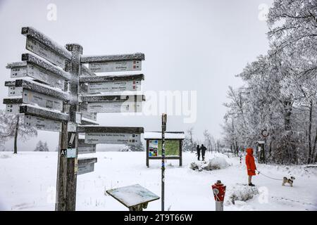 Winterberg, Germania. 27 novembre 2023. Un cartello innevato per gli escursionisti si trova sul Kahler Asten. Il clima freddo e umido continua nella Renania settentrionale-Vestfalia. Oltre i 300-400 metri si sono verificate ulteriori nevicate, a basse altitudini pioggia o nevicate. (Al dpa "il clima umido e freddo continua in NRW - neve fresca ad alta quota") crediti: Oliver Berg/dpa/Alamy Live News Foto Stock