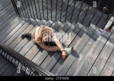 Una donna che conduce uno stile di vita sano, va per sport in strada, esegue un esercizio su stretching dei muscoli delle gambe, siede in una longitudinale Foto Stock