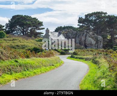 Una casa in pietra si fonde con fiori e rocce giganti sullo sfondo Foto Stock