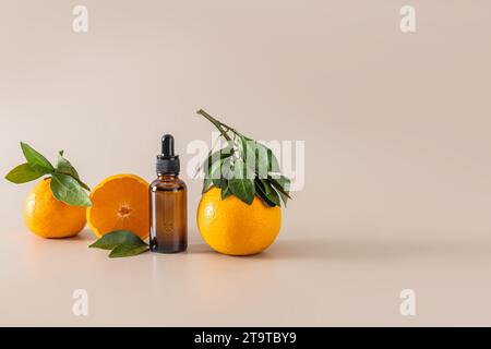 Prodotto cosmetico in bottiglia con contagocce tra mandarini maturi su sfondo beige. Concetto di bellezza e cosmetici naturali. Vitamina C. Foto Stock