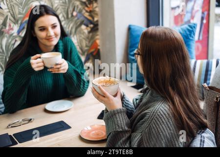 Disintossicazione digitale amici. Due amici si godono una conversazione faccia a faccia con un caffè in caffetteria, disintossicazione digitale impegnandosi in interazioni personali senza Foto Stock