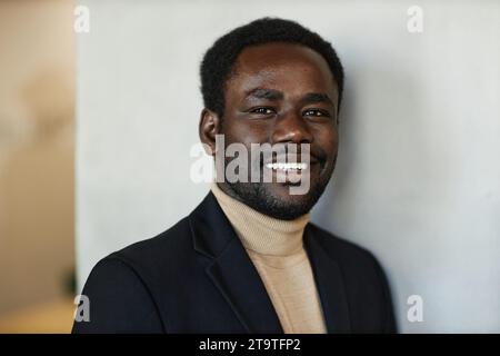 Allegro giovane uomo nero che indossa un abito che guarda la fotocamera in un primo piano medio, spazio per copiare Foto Stock