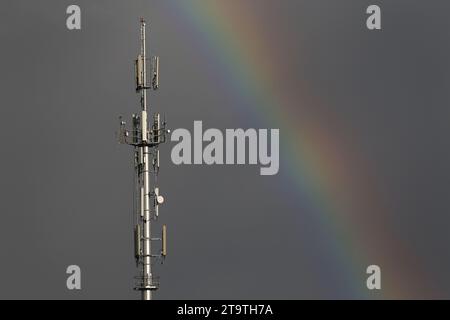 Un montante per telefono cellulare può essere visto con un arcobaleno dietro. Foto Stock