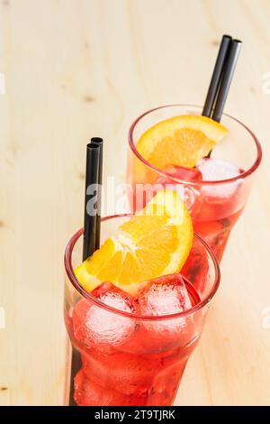 due bicchieri di aperitivo con spritz cocktail aperol con fette d'arancia e cubetti di ghiaccio su tavola di legno Foto Stock