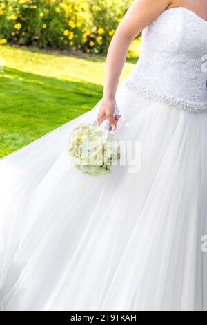 la sposa tiene in mano un bouquet di fiori in un giardino verde Foto Stock