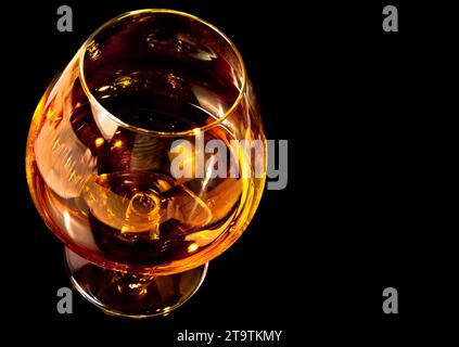 snifter di brandy in elegante tipico vetro cognac su sfondo nero con spazio per il testo Foto Stock