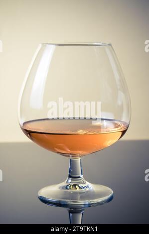 snifter di brandy in elegante vetro cognac tipico isolato sul tavolo con riflesso Foto Stock