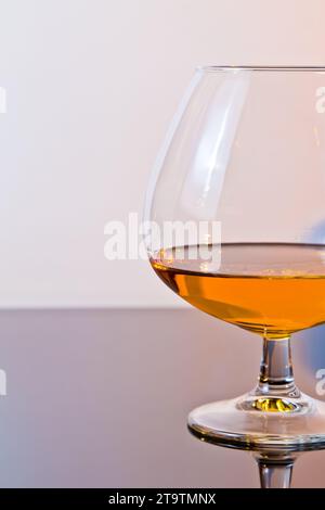 snifter di brandy in un elegante tipico bicchiere di cognac su sfondo chiaro, con spazio per il testo Foto Stock