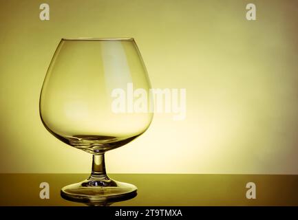 annaffiatoio vuoto di brandy in un elegante bicchiere tipico di cognac sul tavolo in un'atmosfera calda Foto Stock