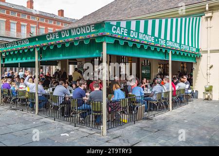 Turisti e gente del posto che si gustano beignets e caffè presso il famoso caffè Cafe du Monde nel quartiere francese di New Orleans, Louisiana Foto Stock