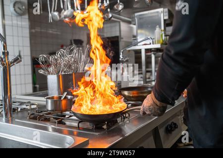 Il fiamma dello chef professionista in cucina in una padella su una stufa a gas. Immagine del concetto di cucina dello chef dell'hotel di lusso. Foto Stock