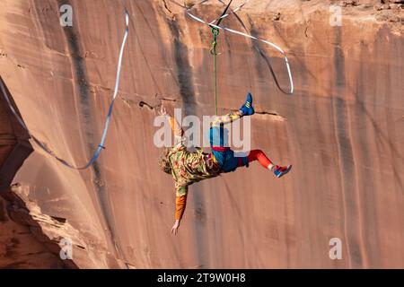 Un Highliner maschile perde l'equilibrio e frusta, o cade fuori dall'Highline, in un festival Highline nello Utah. La sua imbracatura protettiva e il guinzaglio lo tengono lontano Foto Stock