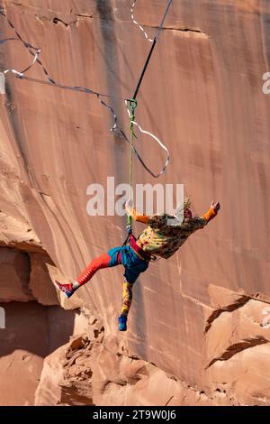 Un Highliner maschile perde l'equilibrio e frusta, o cade fuori dall'Highline, in un festival Highline nello Utah. La sua imbracatura protettiva e il guinzaglio lo tengono lontano Foto Stock