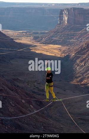 Vista teleobiettivo di un uomo che cammina su una linea principale al GGBY World Highline Festival nel Mineral Canyon vicino a Moab, Utah. Foto Stock