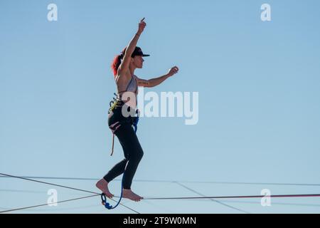 Una giovane donna che cammina su una linea principale al GGBY World Highline Festival nel Mineral Canyon vicino a Moab, Utah. Foto Stock