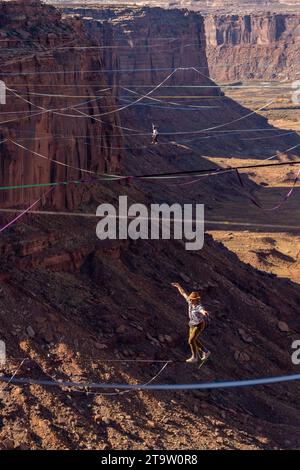 Vista teleobiettivo di un uomo che cammina su una linea principale al GGBY World Highline Festival nel Mineral Canyon vicino a Moab, Utah. Foto Stock