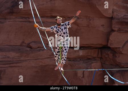 Un uomo in costume che cammina su una cima con un pompelmo al GGBY World Highline Festival nel Mineral Canyon vicino a Moab, Utah. Il pompelmo va a Bal Foto Stock