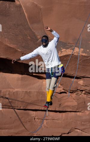 Un giovane nero che cammina su un bendato al GGBY World Highline Festival nel Mineral Canyon vicino a Moab, Utah. Foto Stock