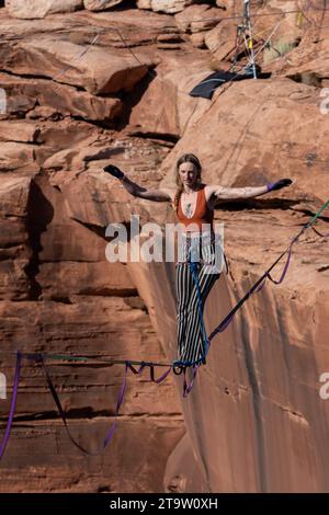 Una giovane donna che cammina su una linea principale al GGBY World Highline Festival nel Mineral Canyon vicino a Moab, Utah. Foto Stock