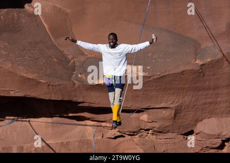 Un giovane nero che cammina su una linea alta tenendo in mano una bibita al GGBY World Highline Festival nel Mineral Canyon vicino a Moab, Utah. Foto Stock