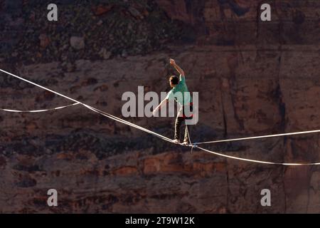 Vista teleobiettivo di un uomo che cammina su una linea principale al GGBY World Highline Festival nel Mineral Canyon vicino a Moab, Utah. Foto Stock