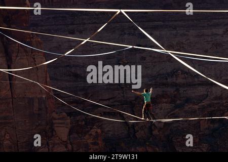 Vista teleobiettivo di un uomo che cammina su una linea principale al GGBY World Highline Festival nel Mineral Canyon vicino a Moab, Utah. Foto Stock