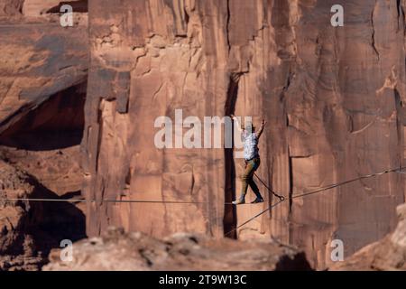 Vista teleobiettivo di un uomo che cammina su una linea principale al GGBY World Highline Festival nel Mineral Canyon vicino a Moab, Utah. Foto Stock