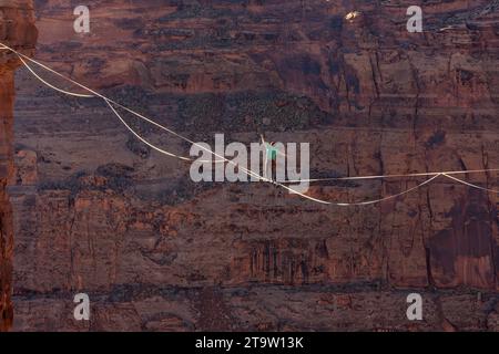 Vista teleobiettivo di un uomo che cammina su una linea principale al GGBY World Highline Festival nel Mineral Canyon vicino a Moab, Utah. Foto Stock