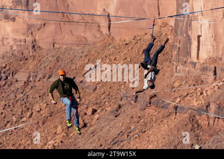 Un Highliner maschile perde l'equilibrio e frulla, o cade fuori dall'Highline in un festival Highline nello Utah. La sua imbracatura protettiva e il guinzaglio lo impediscono Foto Stock