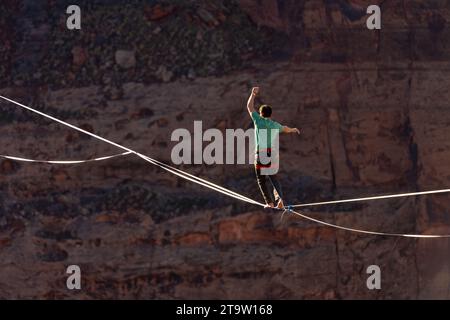 Vista teleobiettivo di un uomo che cammina su una linea principale al GGBY World Highline Festival nel Mineral Canyon vicino a Moab, Utah. Foto Stock