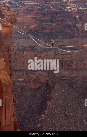 Vista teleobiettivo di un uomo che cammina su una linea principale al GGBY World Highline Festival nel Mineral Canyon vicino a Moab, Utah. Foto Stock