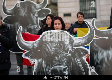 Madrid, Spagna. 27 novembre 2023. Un attivista anti-corrida porta la testa di un toro di cartone durante una protesta davanti all'edificio presidenziale della Comunità di Madrid. Gli attivisti della rete internazionale anti-Bullfighting, con teste di toro e cavalli giganti, svolgono una manifestazione di protesta per l'abolizione della corrida, nel centro di Madrid. Credito: SOPA Images Limited/Alamy Live News Foto Stock