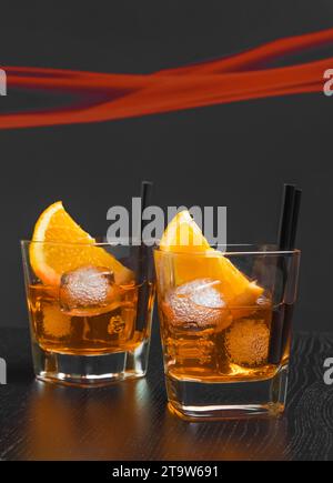 due bicchieri di cocktail con fette d'arancia e cubetti di ghiaccio sul tavolo di legno Foto Stock